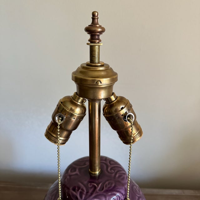 Vintage purple floral ceramic ginger jar style table lamp sits on an detailed etched brass base with filigree detail. It...
