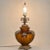 This large vintage brown glass urn table lamp features ornate gold-tone cast metal and hanging clear glass prisms. It...