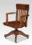 Oak revolving office chair with comb back above the solid seat. Raised up on four cabriole legs terminating in castors....
