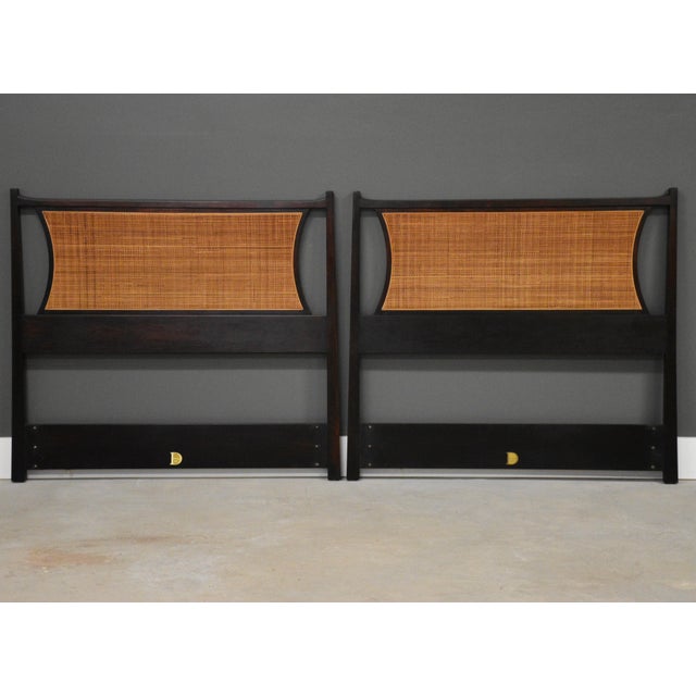 A pair of mid century modern walnut twin headboards with cane backs designed by Edward Wormley for Dunbar. 42.75” wide. 2”...