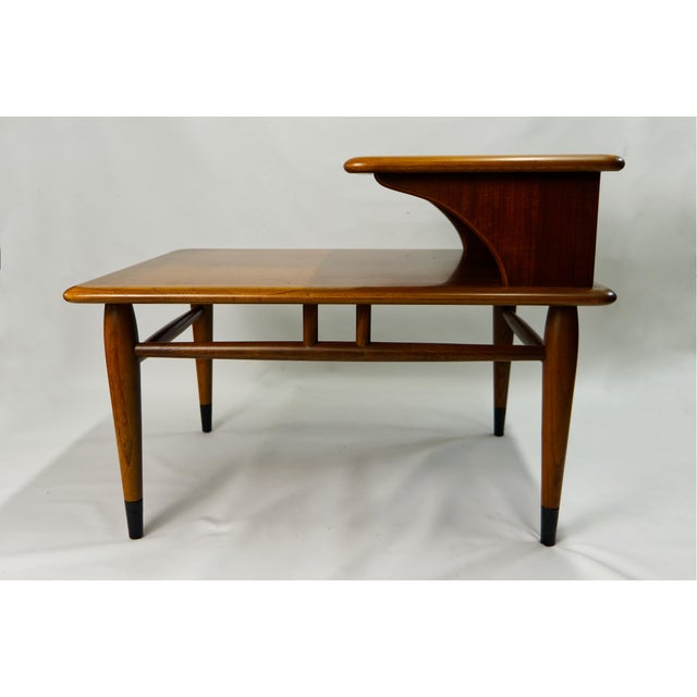 This 1960s Lane Acclaim two-tier side table is a classic example of mid-century modern craftsmanship and design. Made from...
