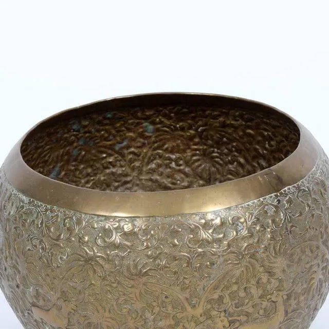 A hand made embossed brass bowl with Indian hunting scenes, among foliate and palm tree designs.
