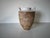 This vintage ceramic vase showcases an elegant fusion of rustic and refined design elements. The textured, earthy base...