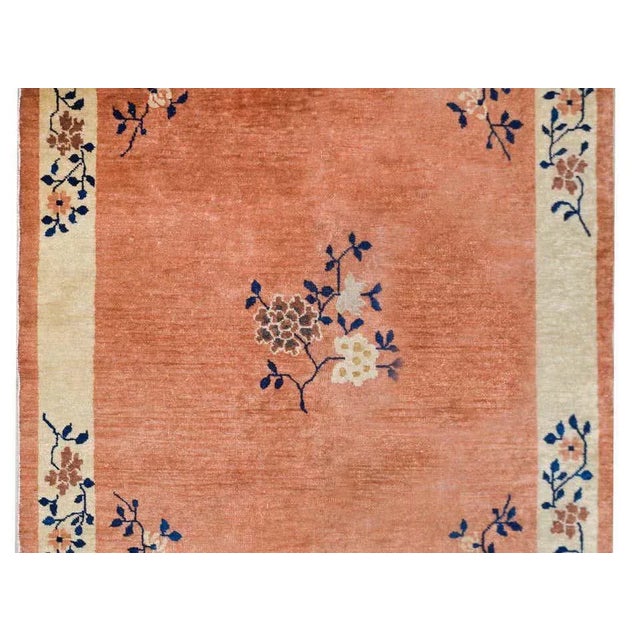 A chic early 20th century Chinese Mandarin rug with a pale orange field with a cream colored striped border with a central...