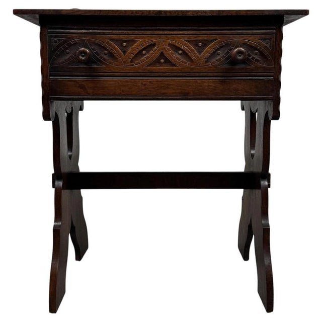 A handsome early 20th-century English side table, finely crafted from oak and distinguished by its carved drawer front,...