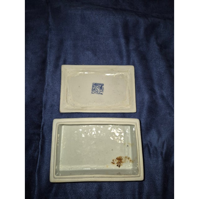 This vintage Chinese rectangular blue and white porcelain lidded box features a hand-painted mountainous river landscape...