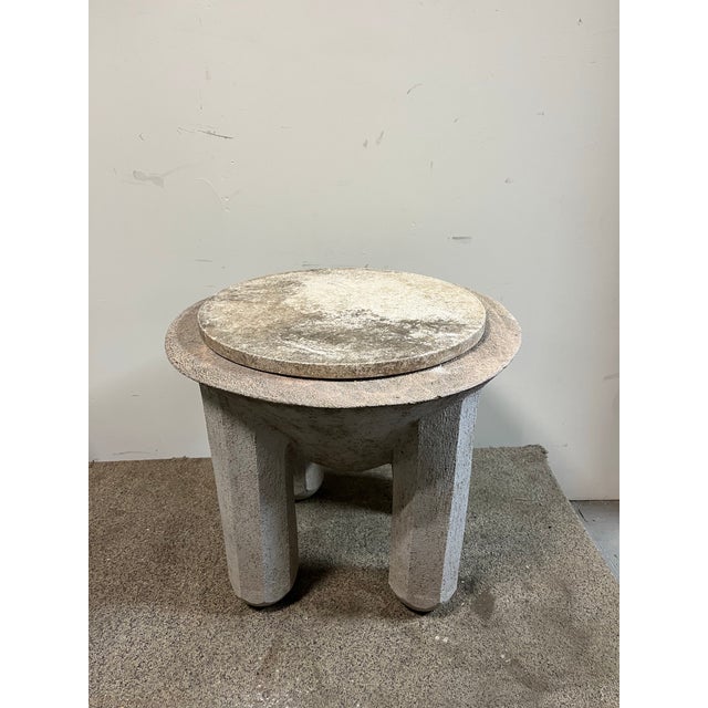 A striking Brutalist stone table featuring a bold, sculptural pedestal design. Crafted with a textured, hand-hewn finish,...