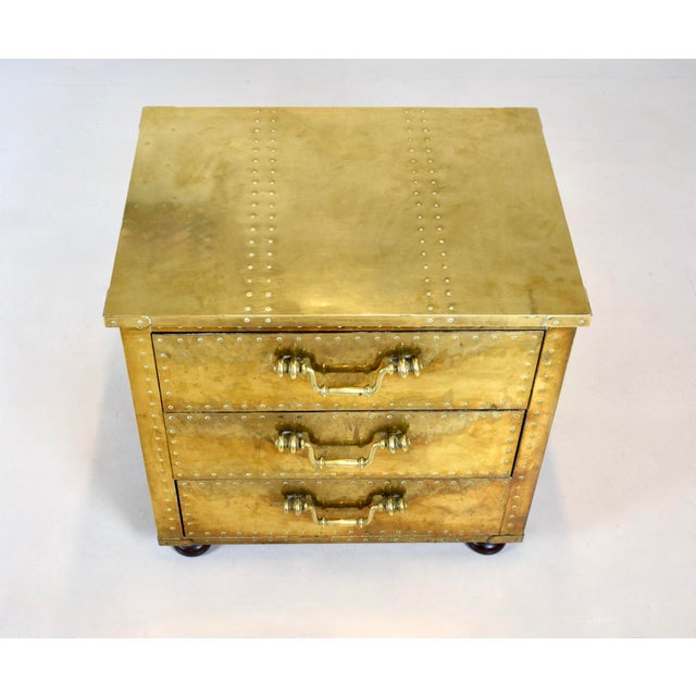 A striking three-drawer brass-clad campaign chest manufactured by Sarreid Ltd., handcrafted in Spain in the 1970s. An...