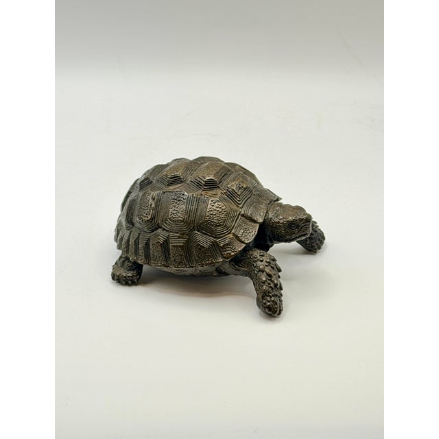A finely crafted bronze tortoise sculpture, rendered with remarkable realism and lifelike detail. Weighing a sturdy 1 lb,...