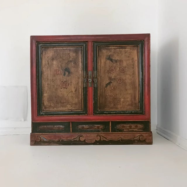 This beautiful side cabinet is from the 20th century. It is built with elm wood, hand painted details, black lacquer,...