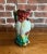 A bold and colorful figural pitcher in the shape of a cockatoo, with vivid red, green, and yellow glaze over raised...