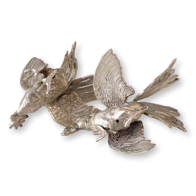 Exquisitely detailed silver-plated rooster figures, each capturing the dynamic movement of fighting cocks with intricately...