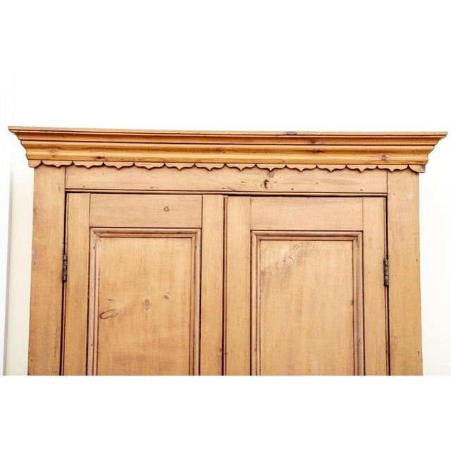 A country chic armoire well crafted in natural honeyed brown pine, showcasing a straight moulded crown with a petaled trim...