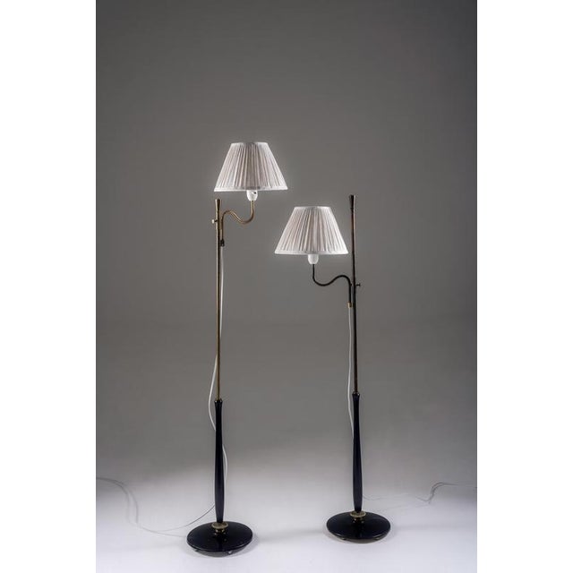 Elegant pair of swedish floor lamps crafted in brass with black-painted wooden stems. Each lamp features a slender...
