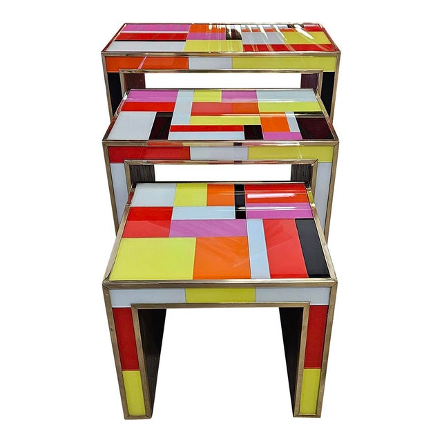 Tri stackable tables, handmade, in wood and covered in colored glass and enriched with golden brass profiles. Dimensions...