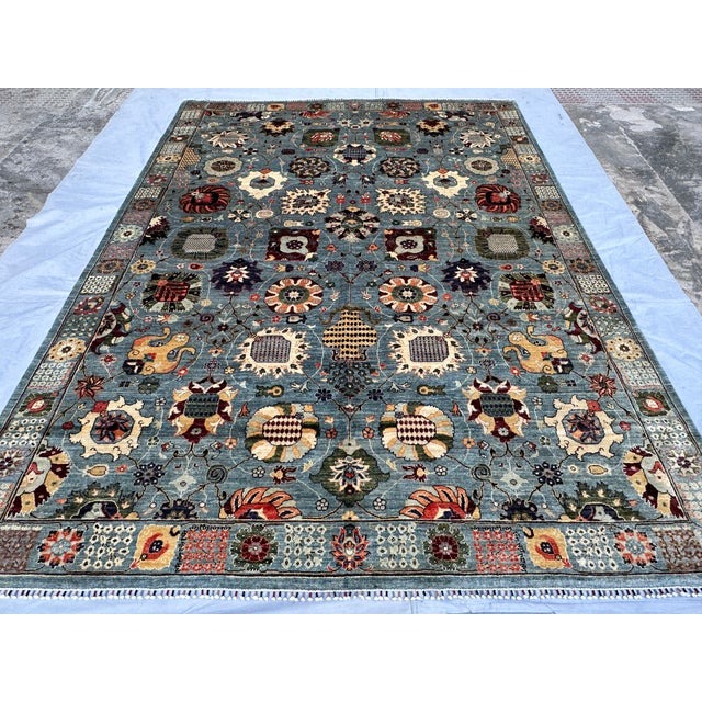 This artistic hand-knotted wool area rug features a stunning and vibrant Suzani tribal design. The main field is decorated...