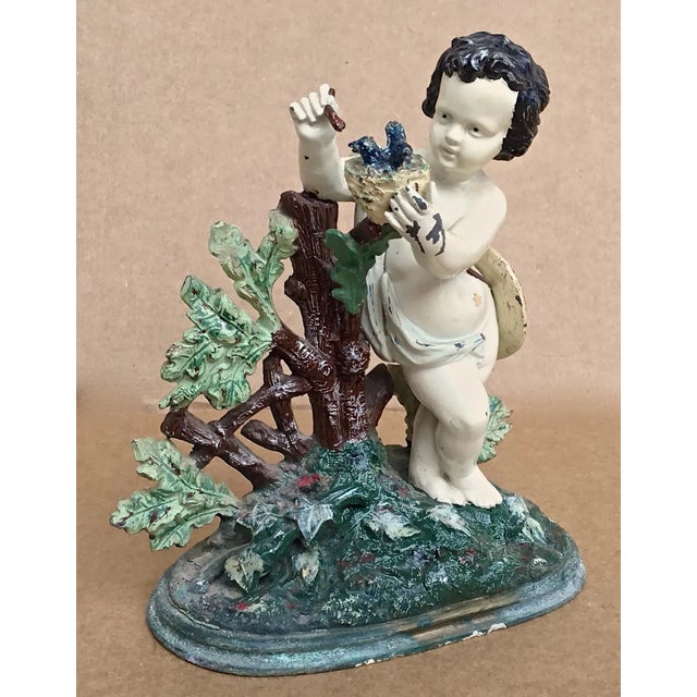 Antique painted cast iron figurine of a cherub feeding birds. No maker's mark. Some paint loss.