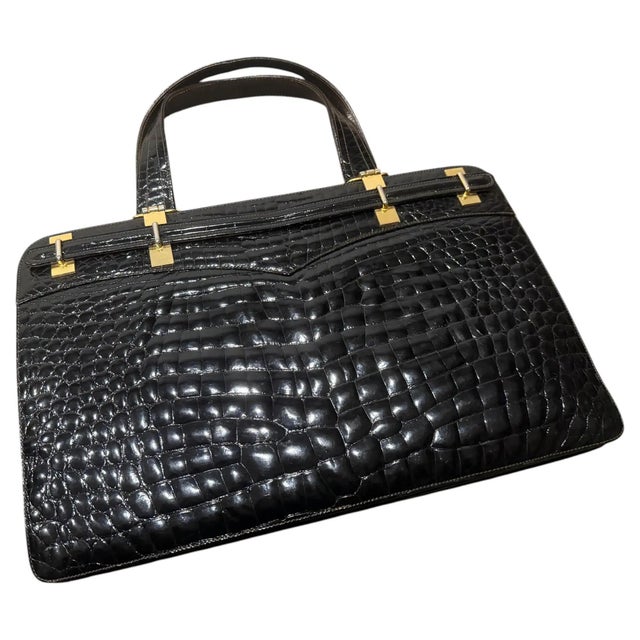 This vintage 1970s Italian handbag is a statement piece of mid-century craftsmanship, featuring glossy, deep black...