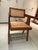 Sculptural vintage wood and woven cane armchair with warm chestnut-brown tones and distinctive architectural lines. The...