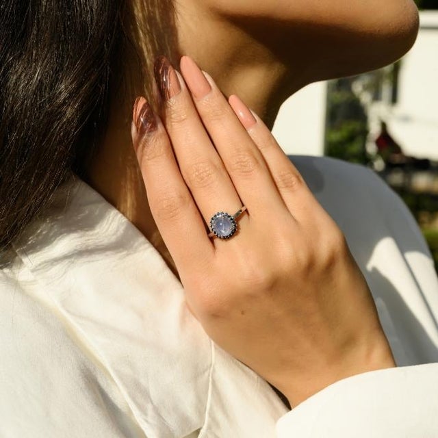 This elegant ring features a 1 oval cut captivating natural cabochon blue star sapphire at the center, weighing...