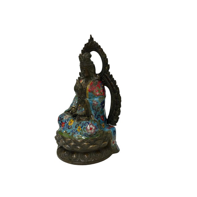 This ornate bronze and cloisonné statue depicts a seated Bodhisattva, likely Guanyin (Avalokiteshvara), captured in a...
