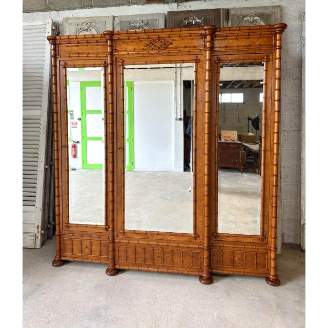 A late 19th-century wardrobe with three doors and drawers. The uprights and ornamentation are in imitation bamboo. The...