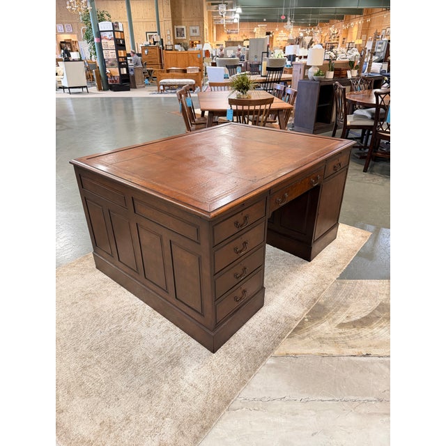 An impressive antique English partners desk embodying the distinguished craftsmanship and architectural refinement of...