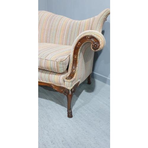 This is a superb quality mahogany settee/couch, with stunning curves, three winged hoof legs, carved arms, covered in Paul...