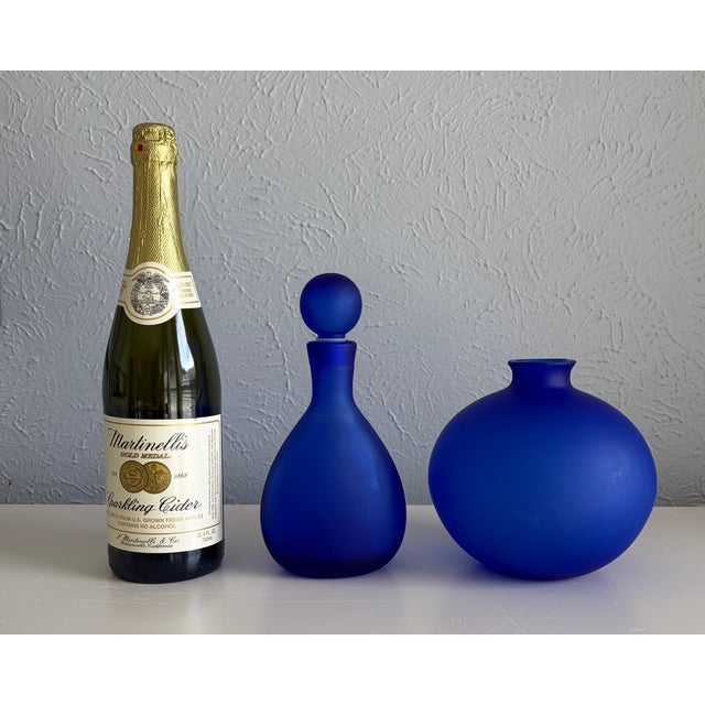 Rich cobalt-blue color and softly frosted surfaces give this coordinating glass duo a sculptural presence. The rounded...