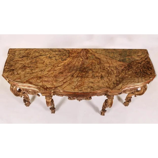 Elegant North Italian 18th century carved and giltwood console table with a painted faux marble top. The table with...
