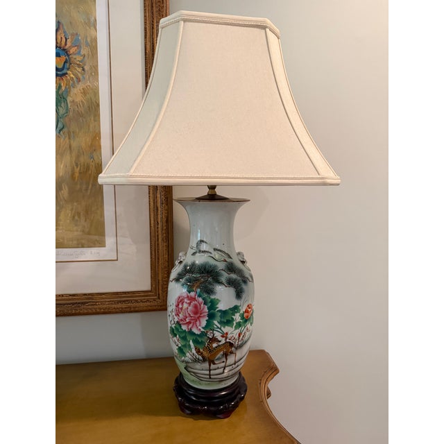 Painted porcelain lamps featuring flowers, deer, and cranes on their fronts. The back side of each lamp is decorated with...