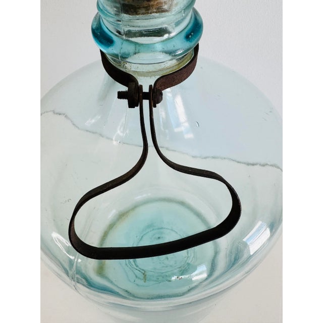 Vintage large glass bottle with a metal handle. The bottle has a blue tint. No marks.