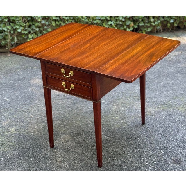 A solid mahogany drop leaf side table by Henkel Harris furniture with 2 drawers having solid brass. The 2 side leaves have...
