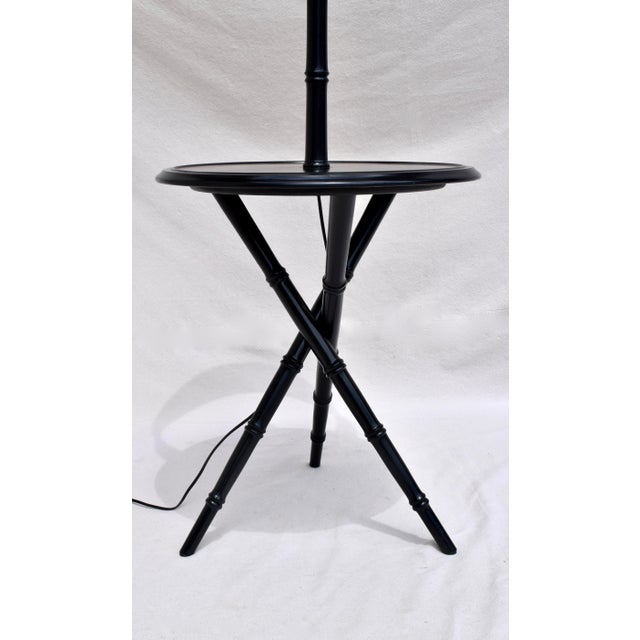 A mid-20th century black lacquer table with lamp, supported on faux bamboo stem and tripod base. Includes the original...