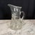 Elegant antique hand-blown clear glass pitcher featuring a finely wheel-etched floral and foliate motif with a delicately...