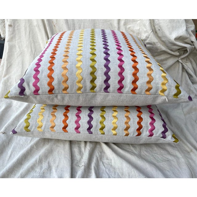 D.V. KAP Home "Samba Blossom" Rainbow Stripe Throw Pillow in a beige linen with rainbow ribbon on the front and solid on...