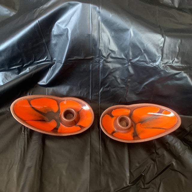 This is a pair of 1970s Royal Haeger Pottery candlestick holders. They are glazed in bright orange and brown.