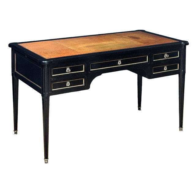 An elegant double-sided French writing desk or table of ebonized wood with gilt accents in the Louis XVI style. Featuring...