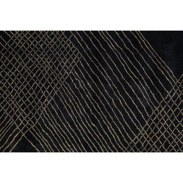 Abylia is a striking contemporary hand-knotted wool rug crafted in deep charcoal black, elevated by intricate antique...