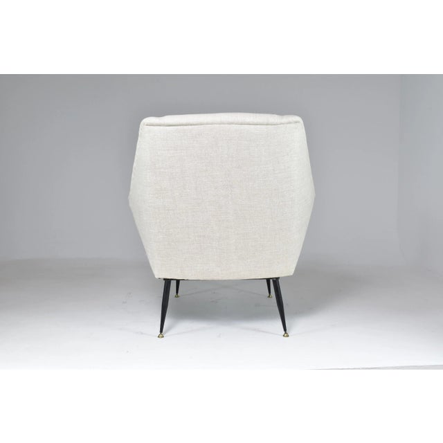 An Italian lounge chair from the 1950s, defined by its light wingback silhouette, generous proportions, and elegantly...