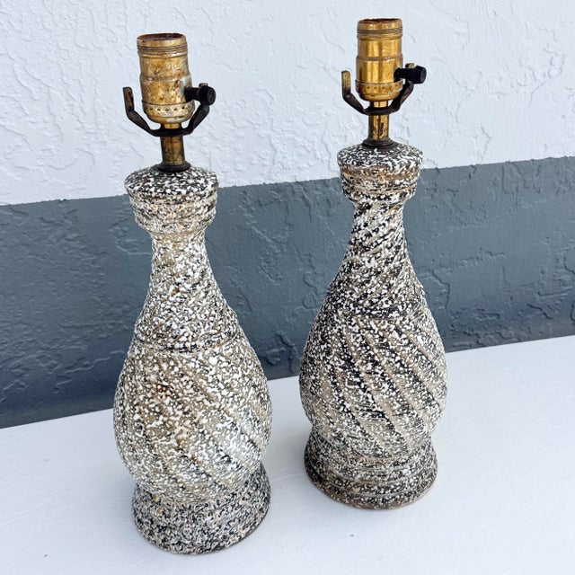 A striking pair of Mid-Century Modern table lamps featuring sculptural bottle-form silhouettes enhanced by a richly...