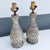A striking pair of Mid-Century Modern table lamps featuring sculptural bottle-form silhouettes enhanced by a richly...