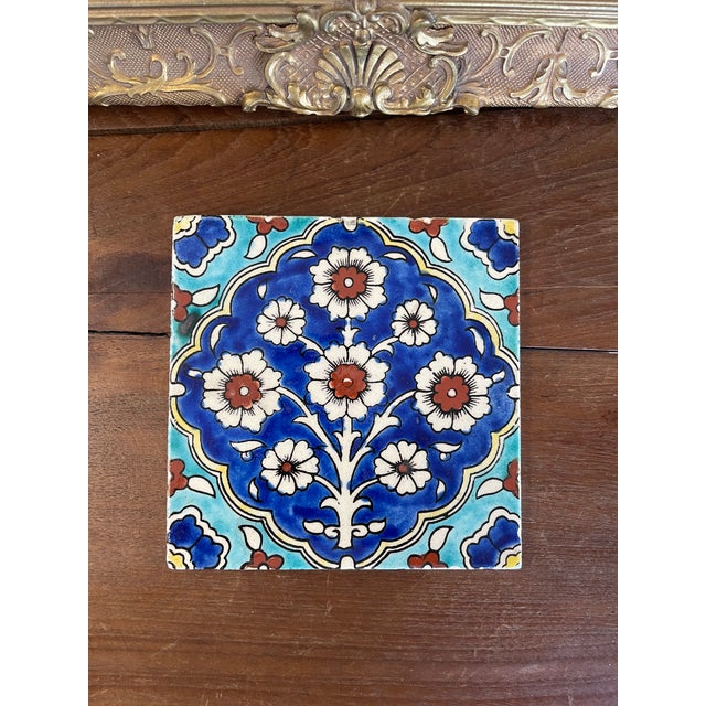 This hand-painted ceramic tile features a traditional Ottoman-inspired floral design in vivid cobalt blue, turquoise, and...