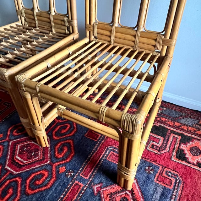 Beautiful pair of vintage rattan dining chairs featuring a sculptural geometric backrest and classic bamboo-style frame....
