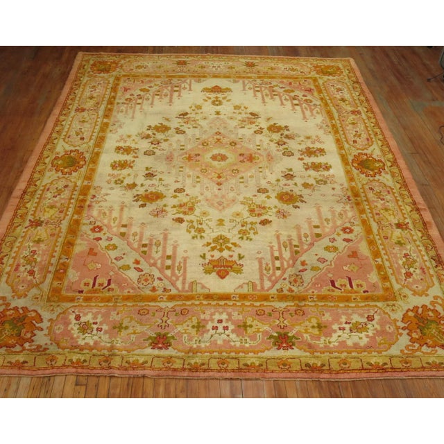 Excellent condition antique Turkish Oushak rug circa 1900-1910. Ivory ground with predominant accents in bright pink and...