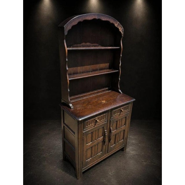A charming and highly decorative Arts & Crafts oak dresser cabinet, dating from the early 20th century and displaying...