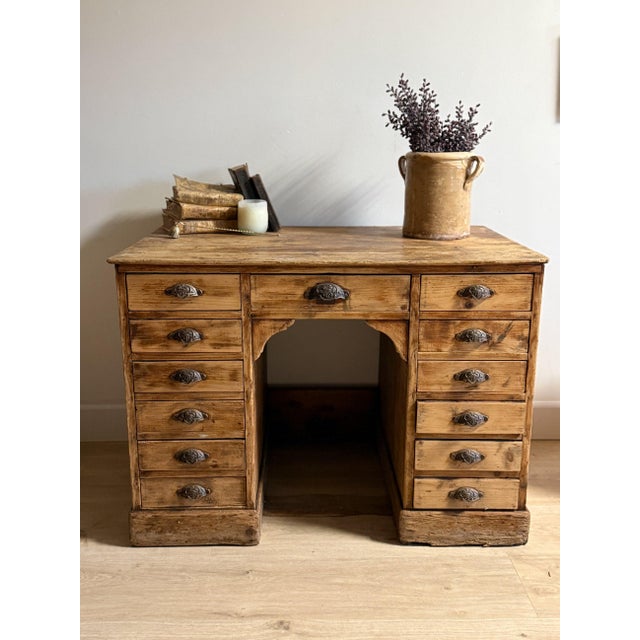 This antique French desk is a beautifully timeworn example of practical craftsmanship, featuring a solid, generously...