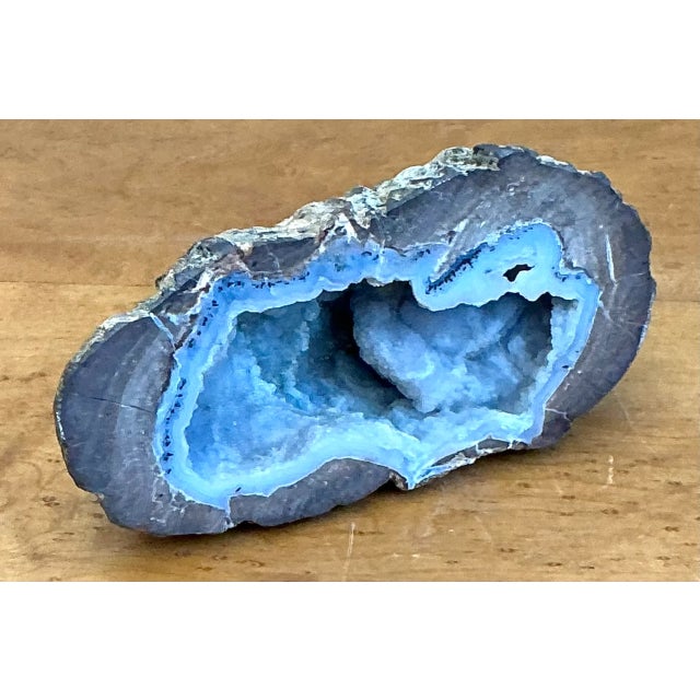 Distinguished by vivid concentric chalcedony banding and an open crystalline cavern, this natural blue agate quartz geode...