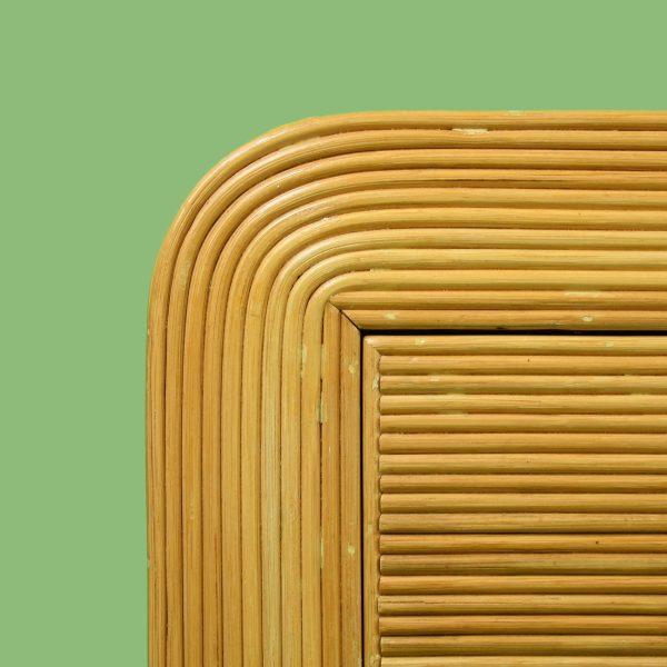 A pencil reed nightstand in the Crespi style, its fine reeds wrapping the case in a shimmering, radiating weave. A drawer...