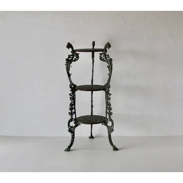 Vintage Victorian-style ornate cast iron three-tier plant stand featuring decorative openwork round shelves and sculptural...